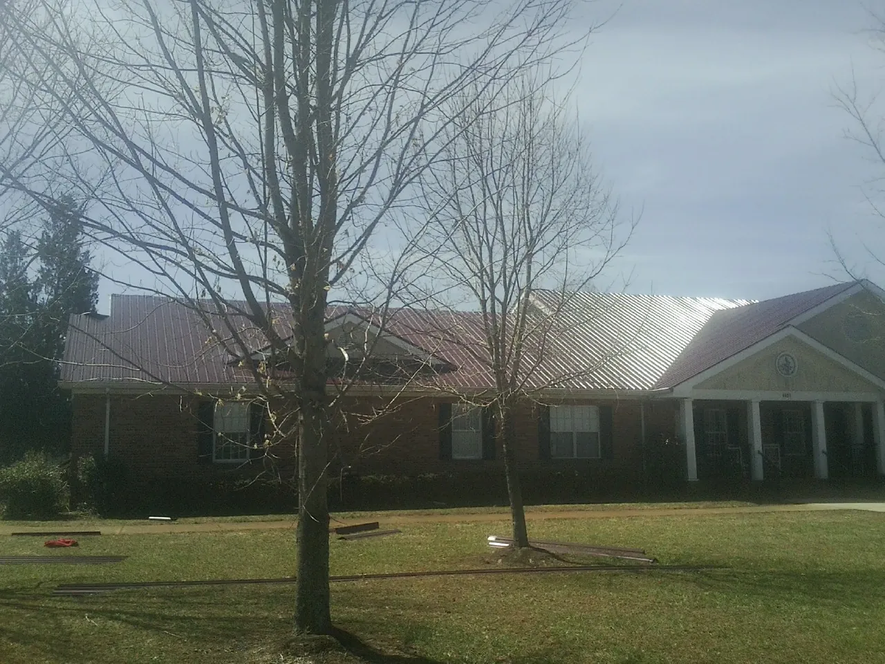 Red metal roof on a brick building seen from the front lawn in Helenwood