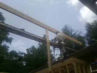 Carpenter setting a ridge beam over a new addition frame — Ice Dam Removal by Roofing Brothers in Helenwood