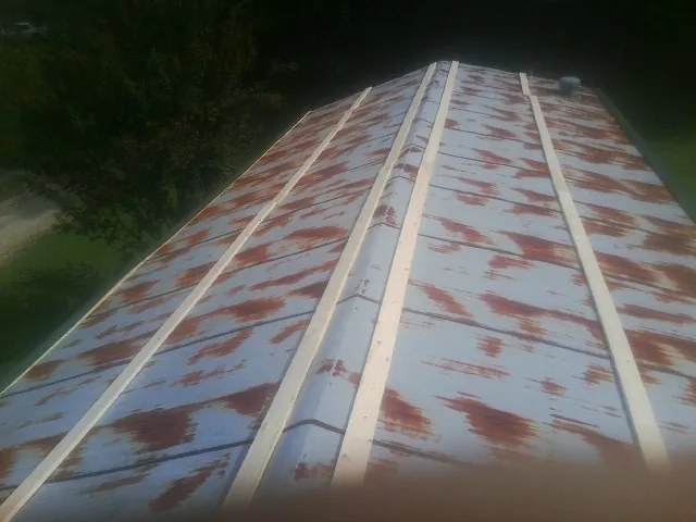 Rusted metal roof panels with new wood purlins before replacement — Storm Damage Roof Repair in Helenwood by Roofing Brothers