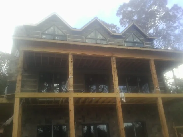 Dormers and porch framing on a large log home under construction — Roof Coating work by our crew in Helenwood