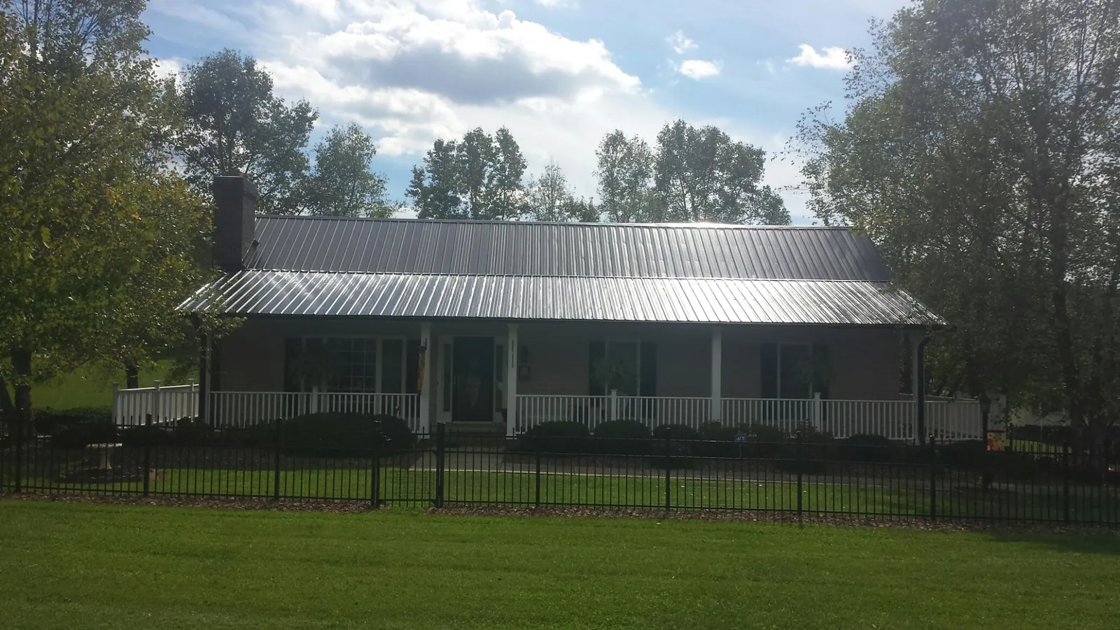 Gray metal roof on a brick ranch with a full width front porch — Gutter Guard Installation work by our crew in Helenwood