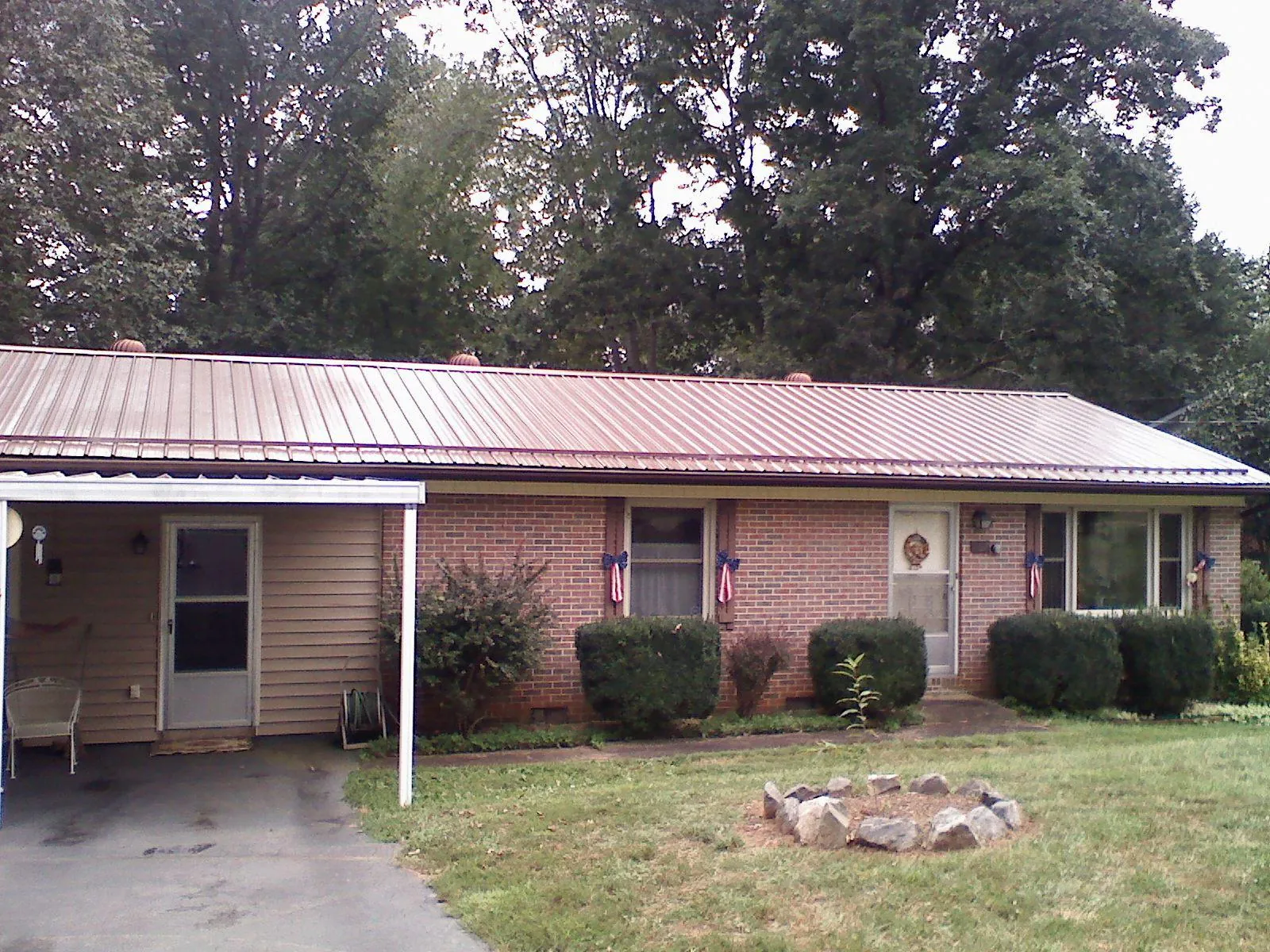 Bronze metal roof and carport on a brick ranch home — Roof Repair work by our crew in Helenwood