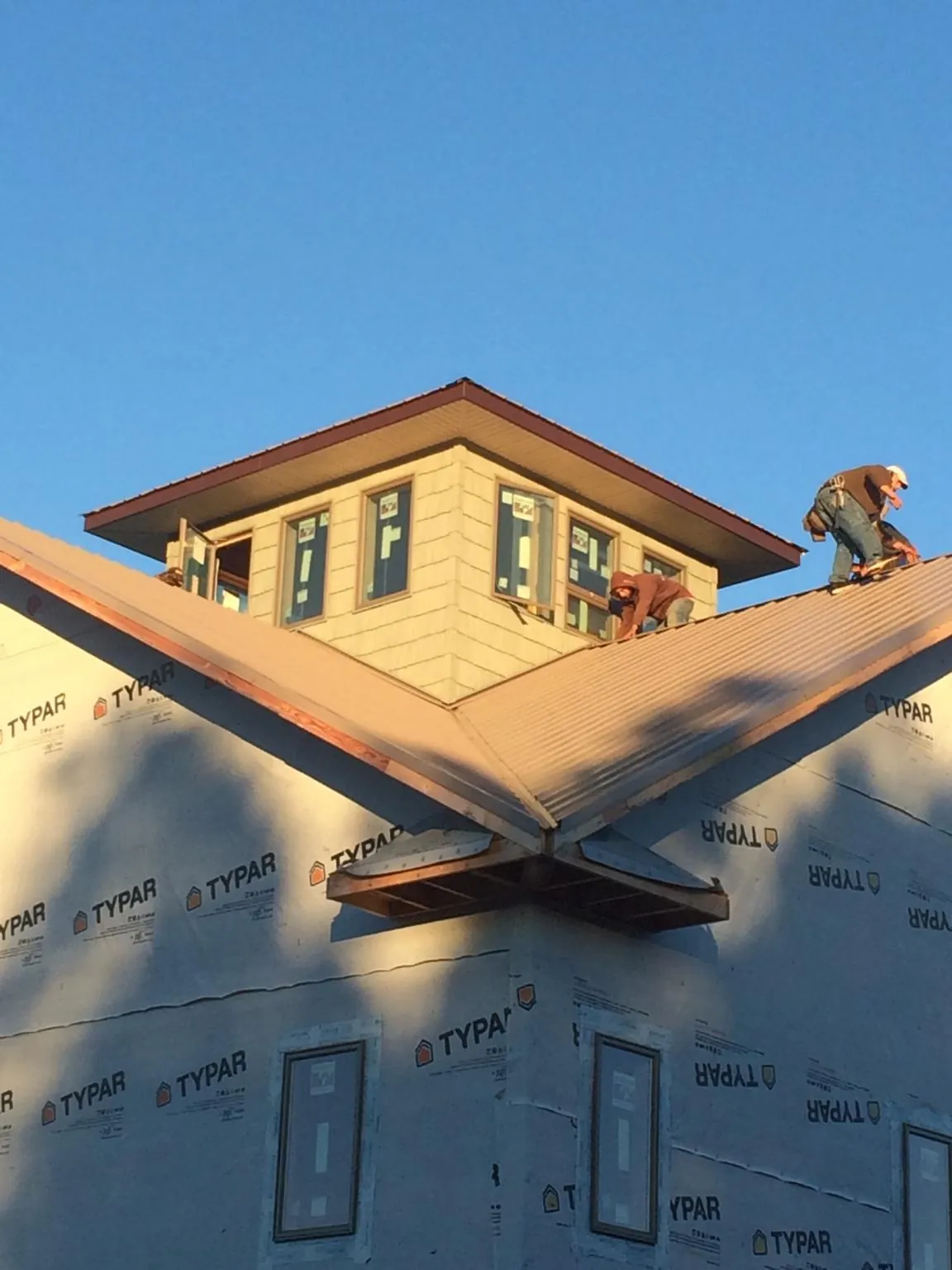 Roofers working around a rooftop cupola on a new metal roof at sunset — Roof Waterproofing in Helenwood by Roofing Brothers